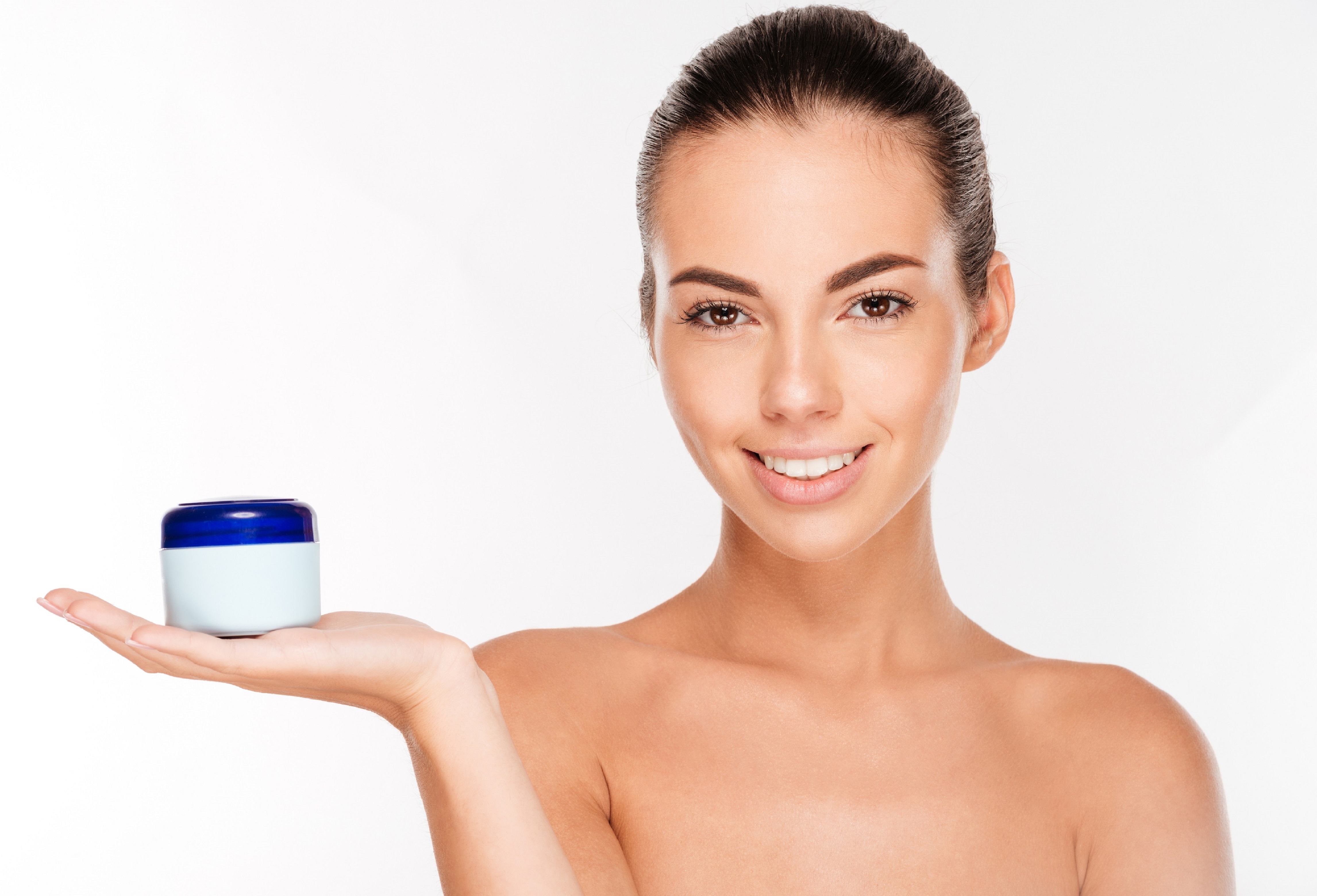 Young beautiful smiling woman with cream bottle isolated on white background